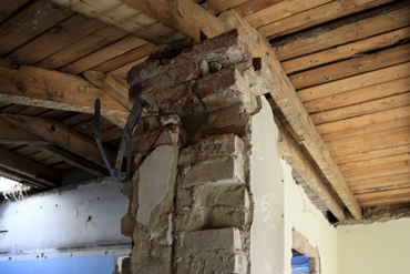 Středové nosné pilíře a nosná zeď, na které byla uložena středová vaznice pultové střechy, byla ponechána a doplněna o ŽB věnec a táhla