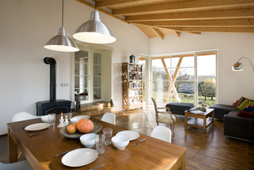 Propojená kuchyň s jídelnou a obývákem tvoří hlavní obytný prostor v dřevěné přístavbě, interiér je zastřešený střechou s přiznanými trámy krovu