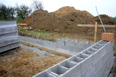 Spodních 0,6 m výšky základových pasů je provedeno z prostého betonu přímo do vykopané rýhy. Vyšší část základu až pod základovou desku je provedena z betonových bednicích dílců šířky 300 mm vyplněných prostým betonem a vyztužené výztuží v každé dutině.